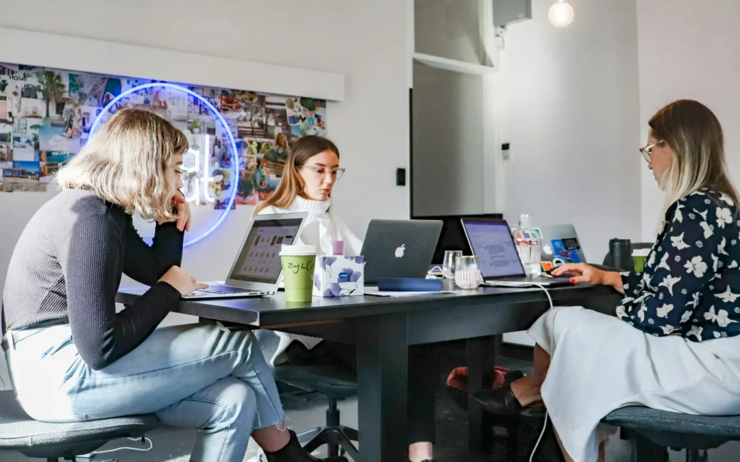 Marketing team collaborating at a desk with laptops in a modern office, discussing digital strategy and campaign planning.